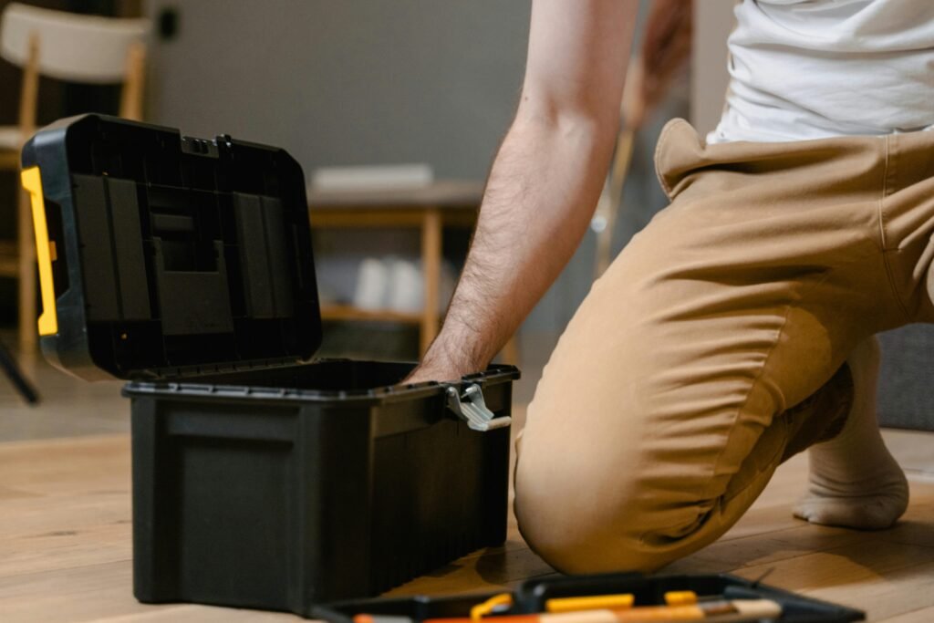 A man opening a tool box indoors, preparing for home repair.